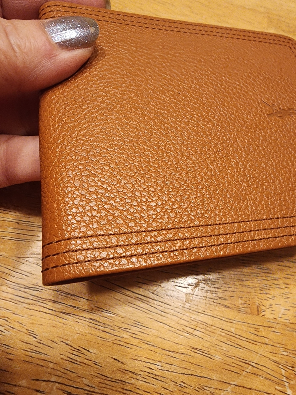 brown grained leather bifold wallet featuring an embossed Saint Laurent monogram